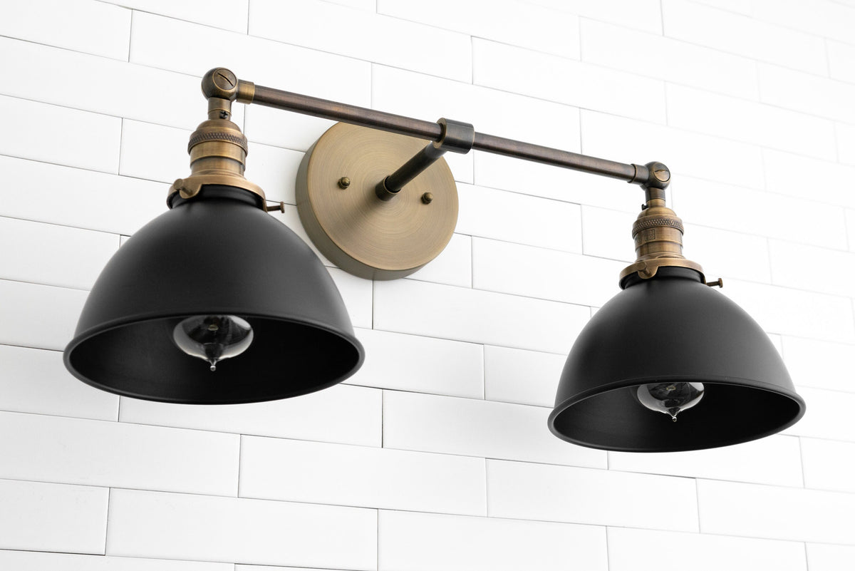 Industrial 2-light black metal wall sconce with adjustable arms and brass accents mounted on white tile wall. - SCONCE MODEL NO. 8791