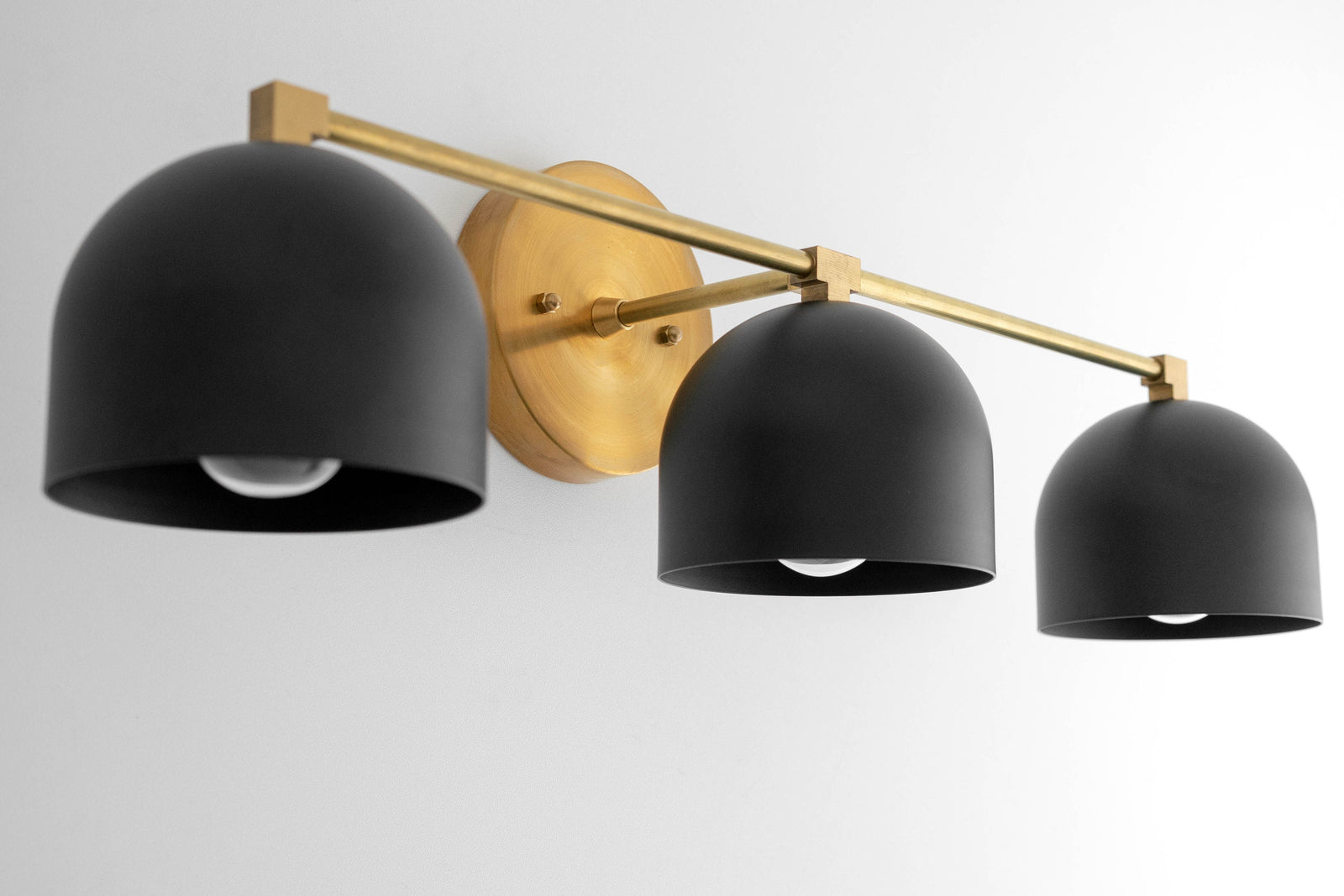 Mid-century modern vanity light with three matte black dome shades and antique brass wall mount and arm. - VANITY LIGHT MODEL NO. 7565