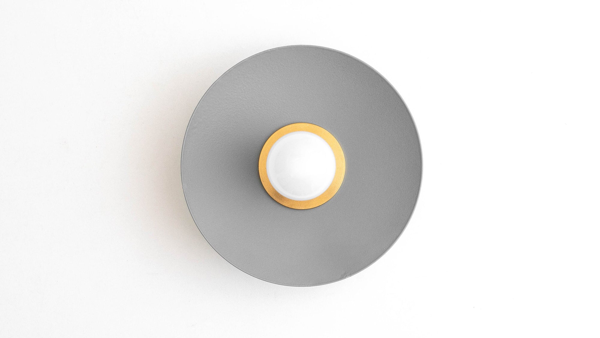 Raw brass and coal blue Scandinavian flush mount sconce with a round backplate and exposed bulb. - SCONCE MODEL NO. 9660
