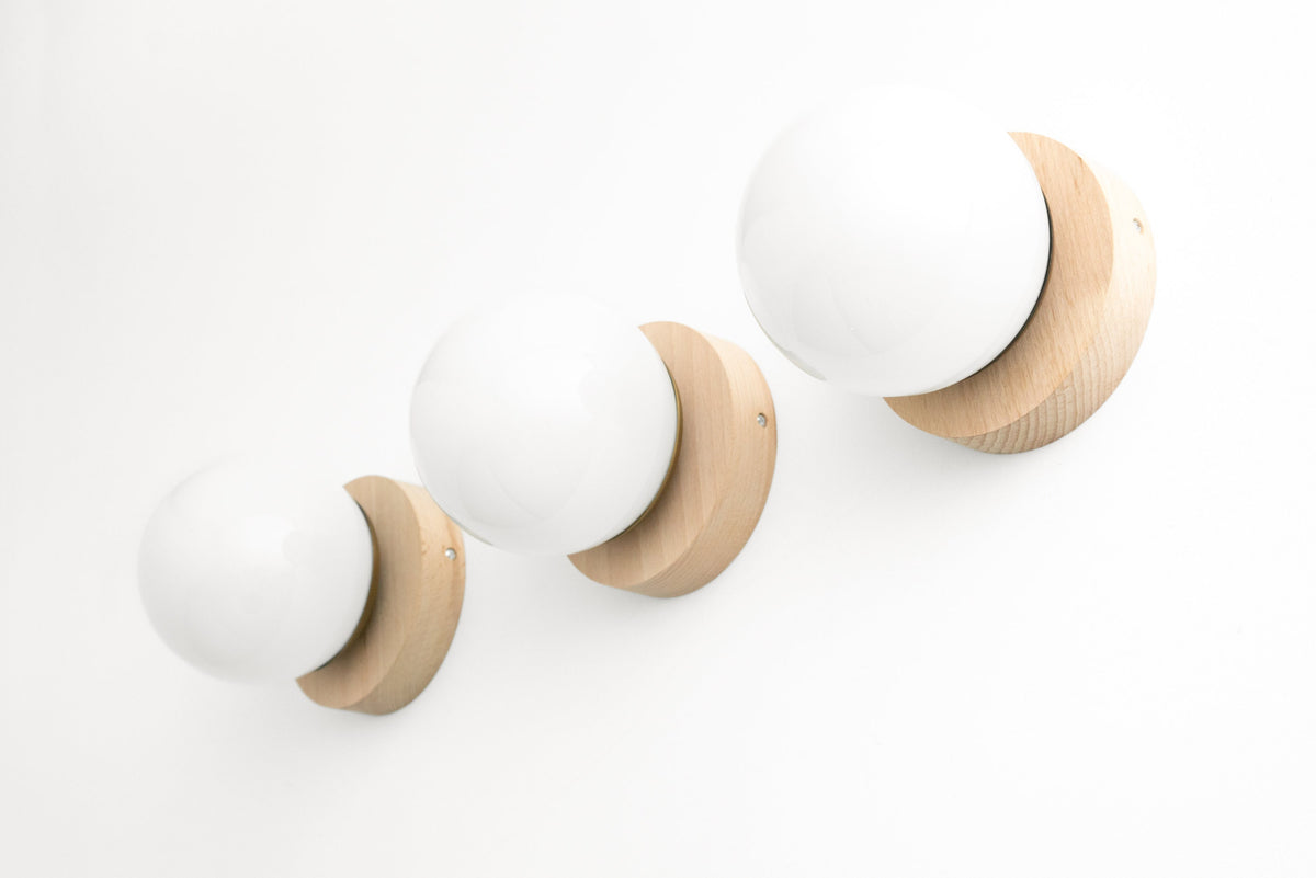 Set of three Scandinavian-style wall sconces with natural beechwood bases and frosted white globe shades. - SCONCE MODEL NO. 5719