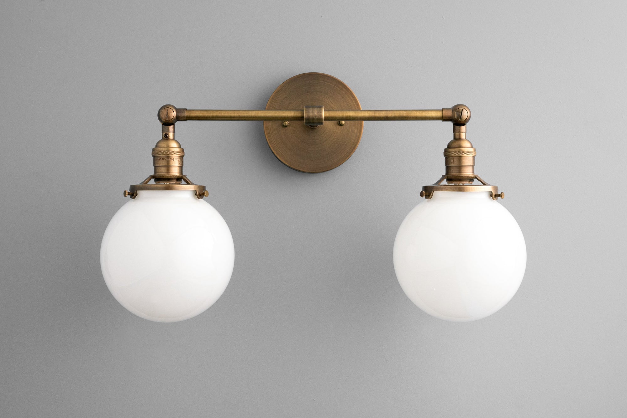 Two-bulb antique brass vanity light with frosted globe shades and industrial design. - VANITY LIGHT MODEL NO. 5348