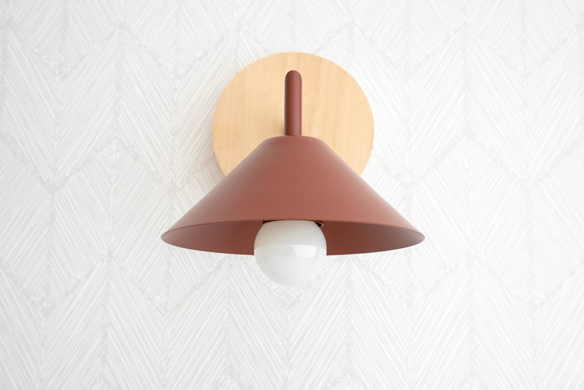 Beechwood wall sconce with a brick red conical shade and exposed bulb against textured white wall. - SCONCE MODEL NO. 1721