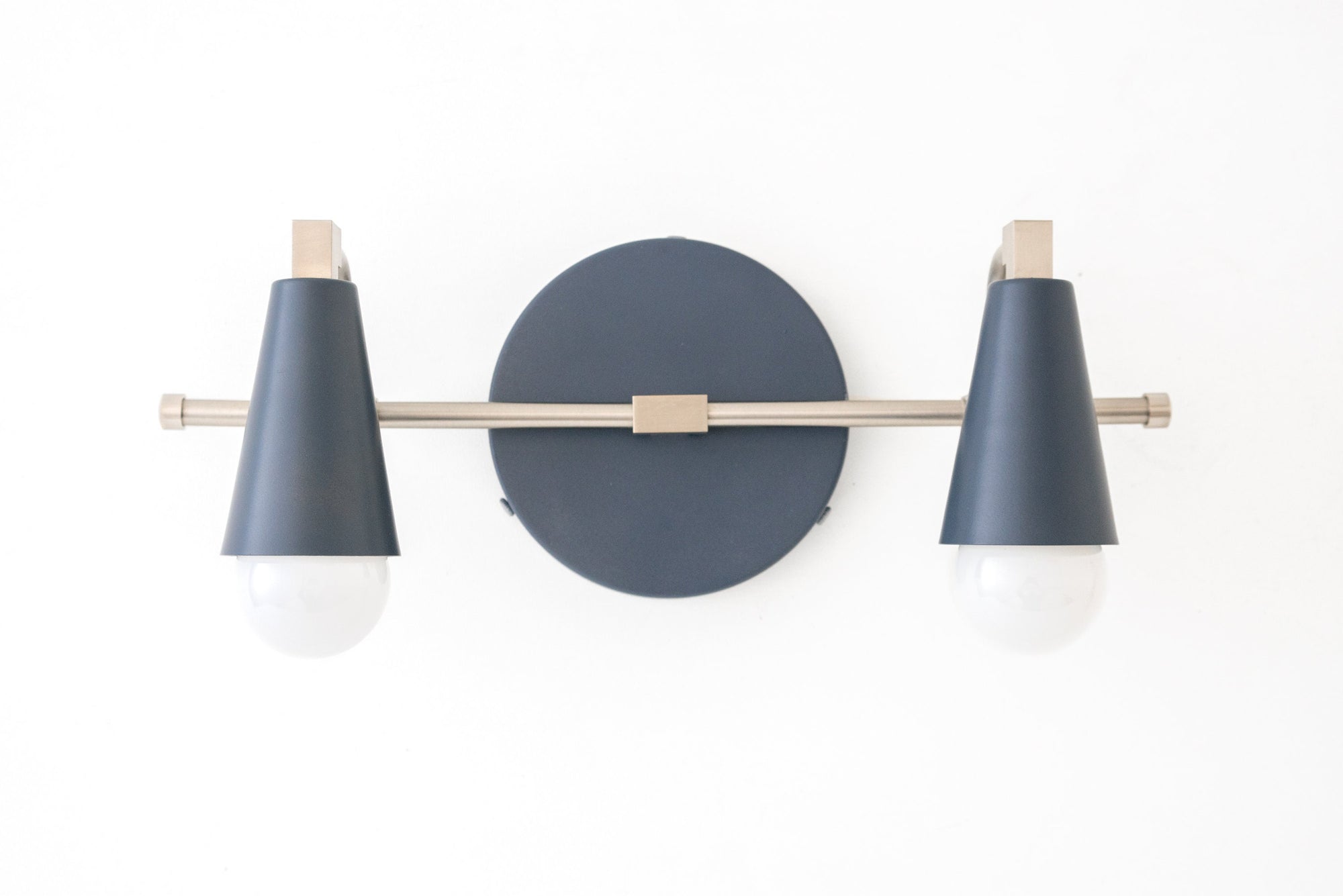 Scandinavian-style vanity light with two black cone shades and brushed nickel accents on a round black wall mount. - VANITY LIGHT MODEL NO. 1229