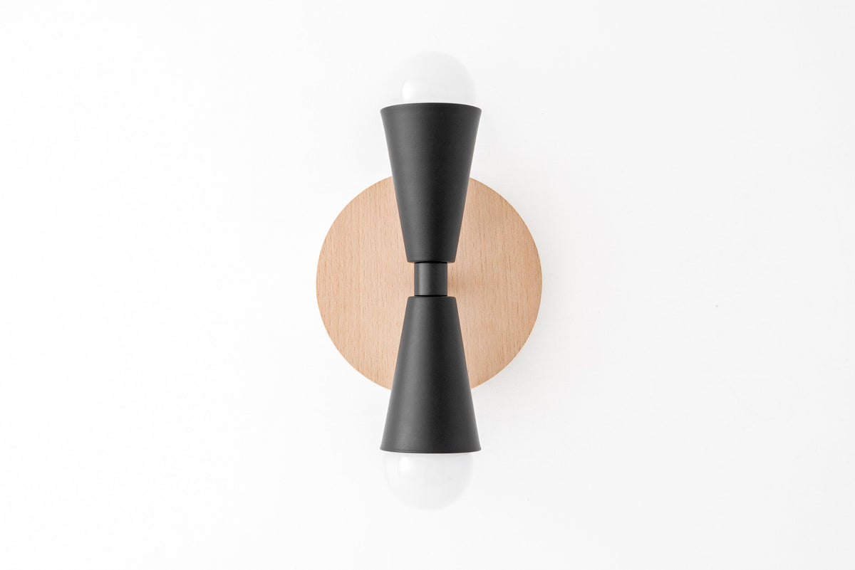 Scandinavian-style sconce with natural beechwood round base and black double cone metal arms holding exposed bulbs top and. - SCONCE MODEL NO. 4717