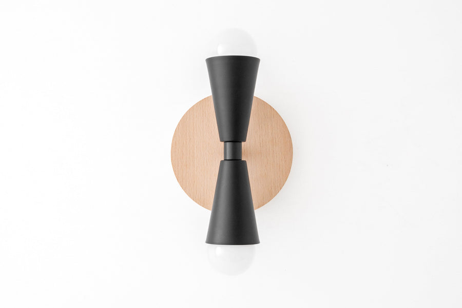 Scandinavian-style sconce with natural beechwood round base and black double cone metal arms holding exposed bulbs top and. - SCONCE MODEL NO. 4717