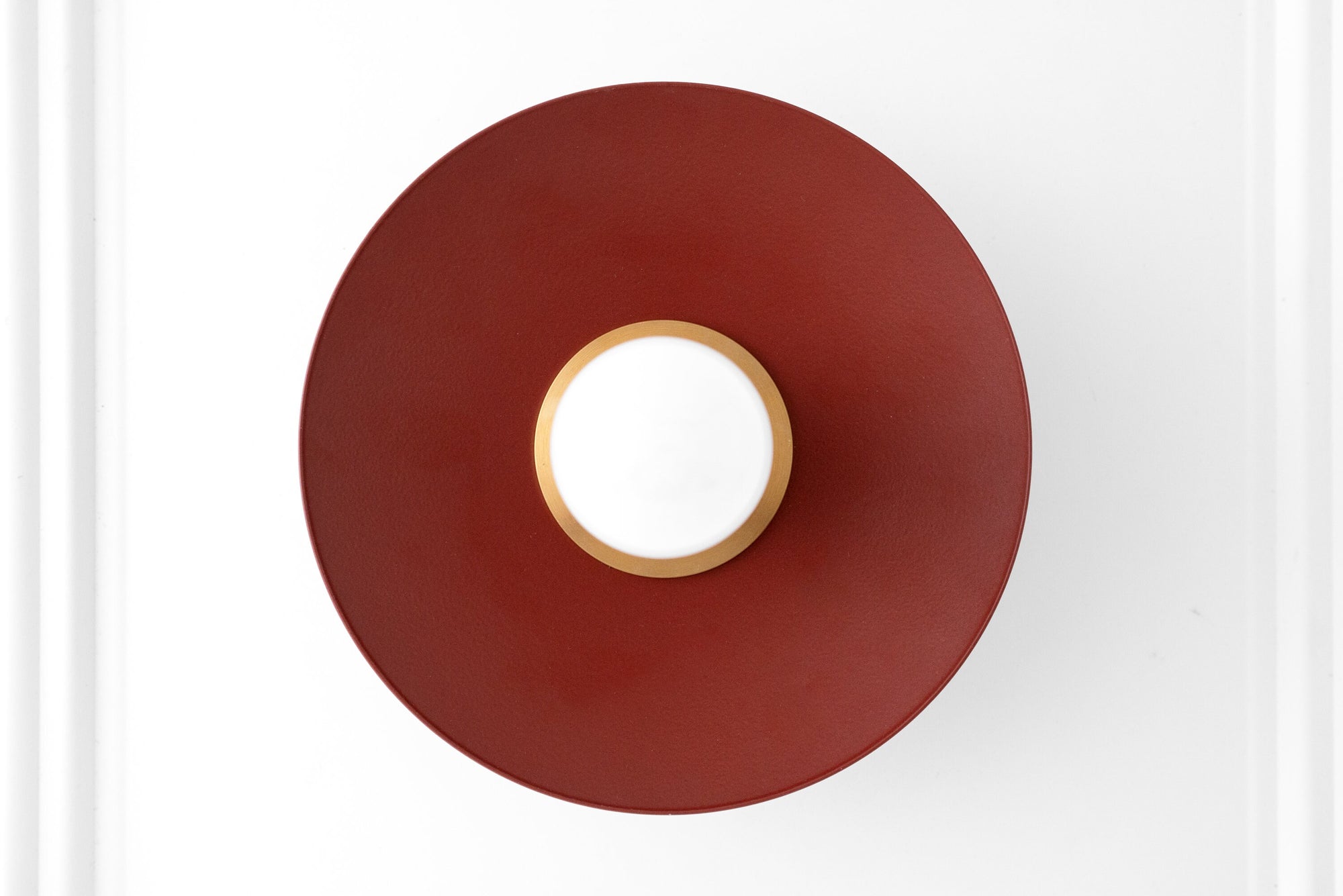 Scandinavian-style wall sconce with raw brass fixture and large brick red circular shade surrounding a bare bulb. - SCONCE MODEL NO. 9660