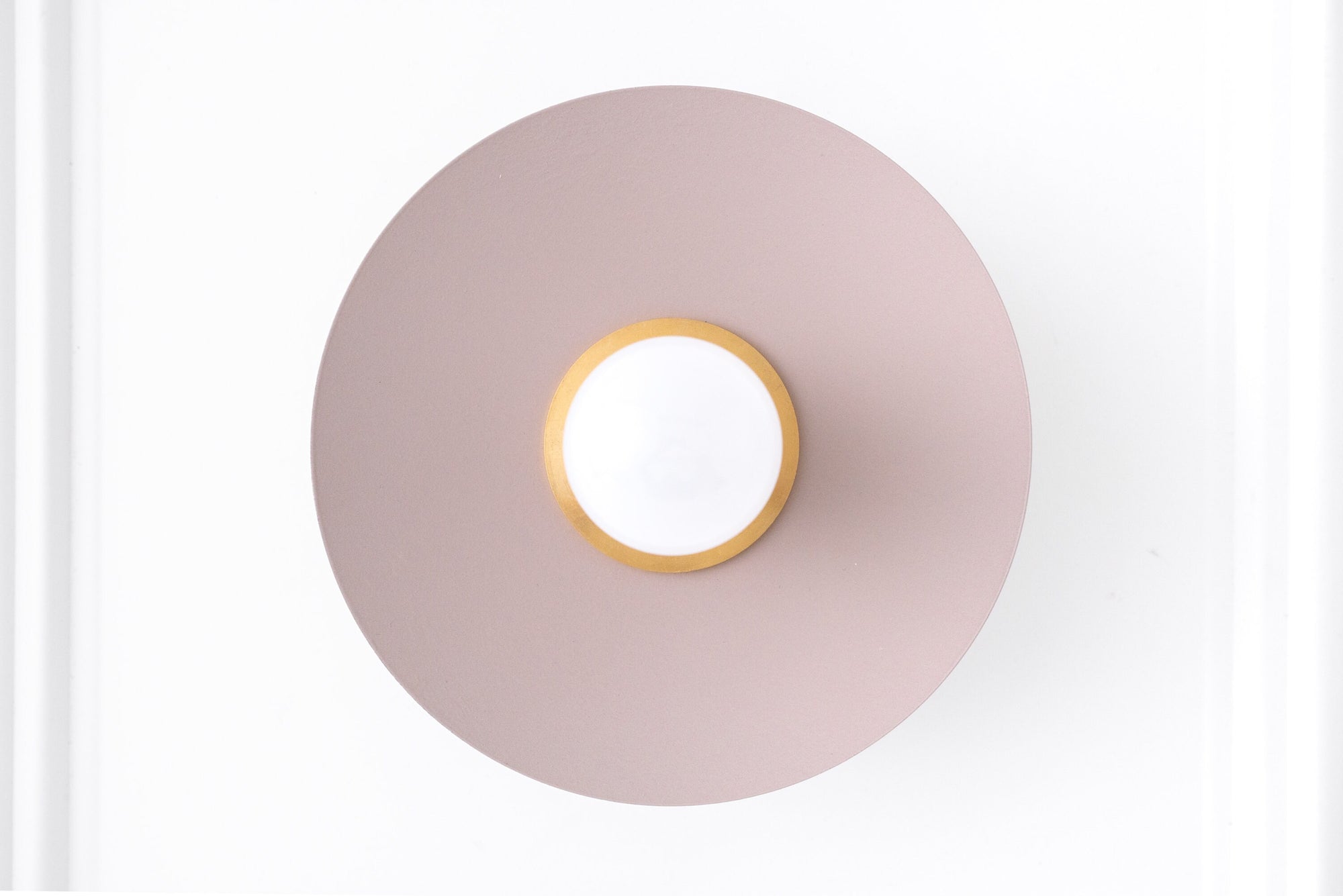 Minimalist raw brass wall sconce with flat mauve circular backplate and exposed round bulb. - SCONCE MODEL NO. 9660
