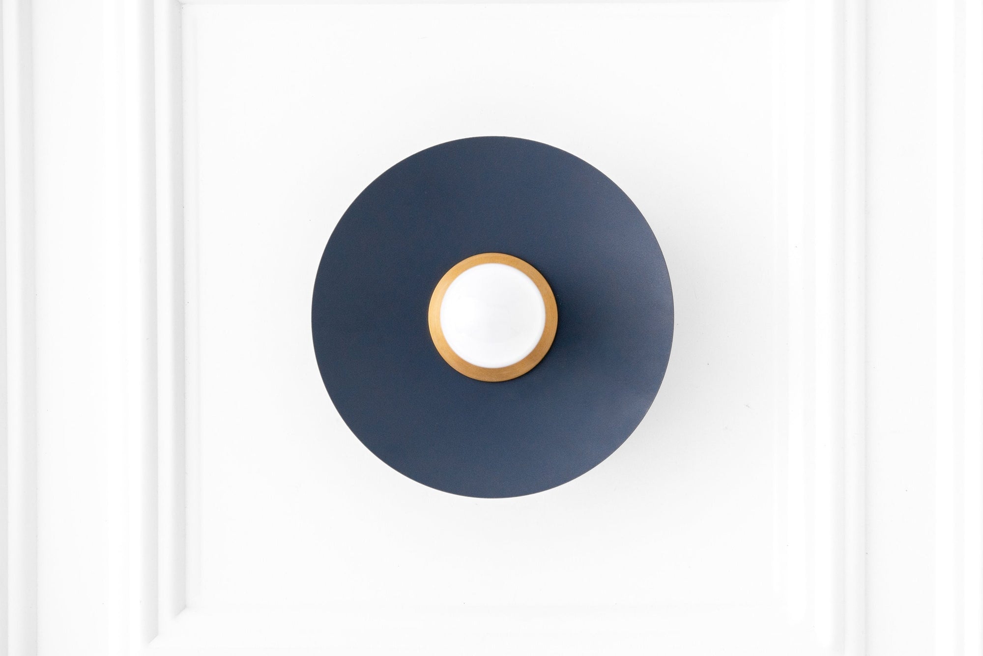 Raw brass sconce with coal blue circular backplate and exposed bulb mounting. - SCONCE MODEL NO. 9660