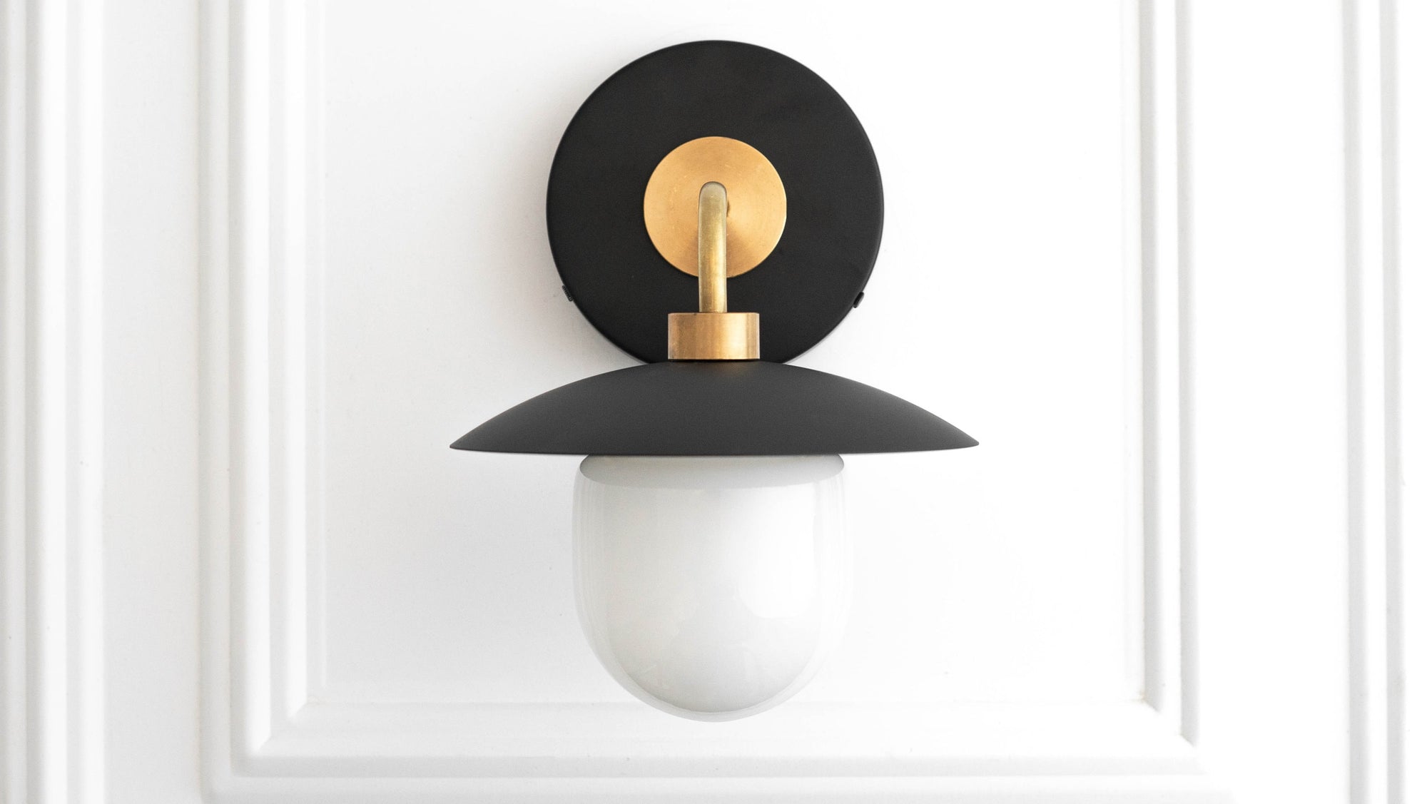 Mid-century modern wall sconce with raw brass mount, black metal shade, and white globe diffuser. - SCONCE MODEL NO. 7039