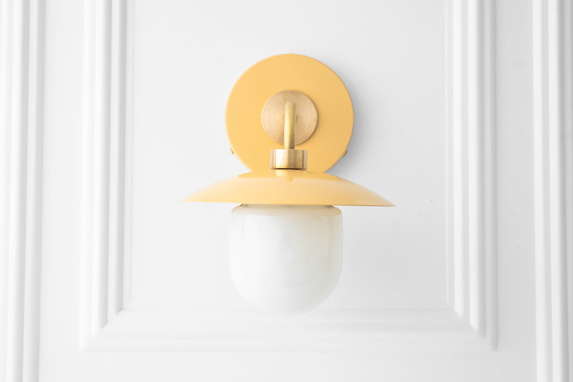 Mid-century modern sconce with raw brass fixture and matte yellow flat circular shade, frosted globe bulb. - SCONCE MODEL NO. 7039