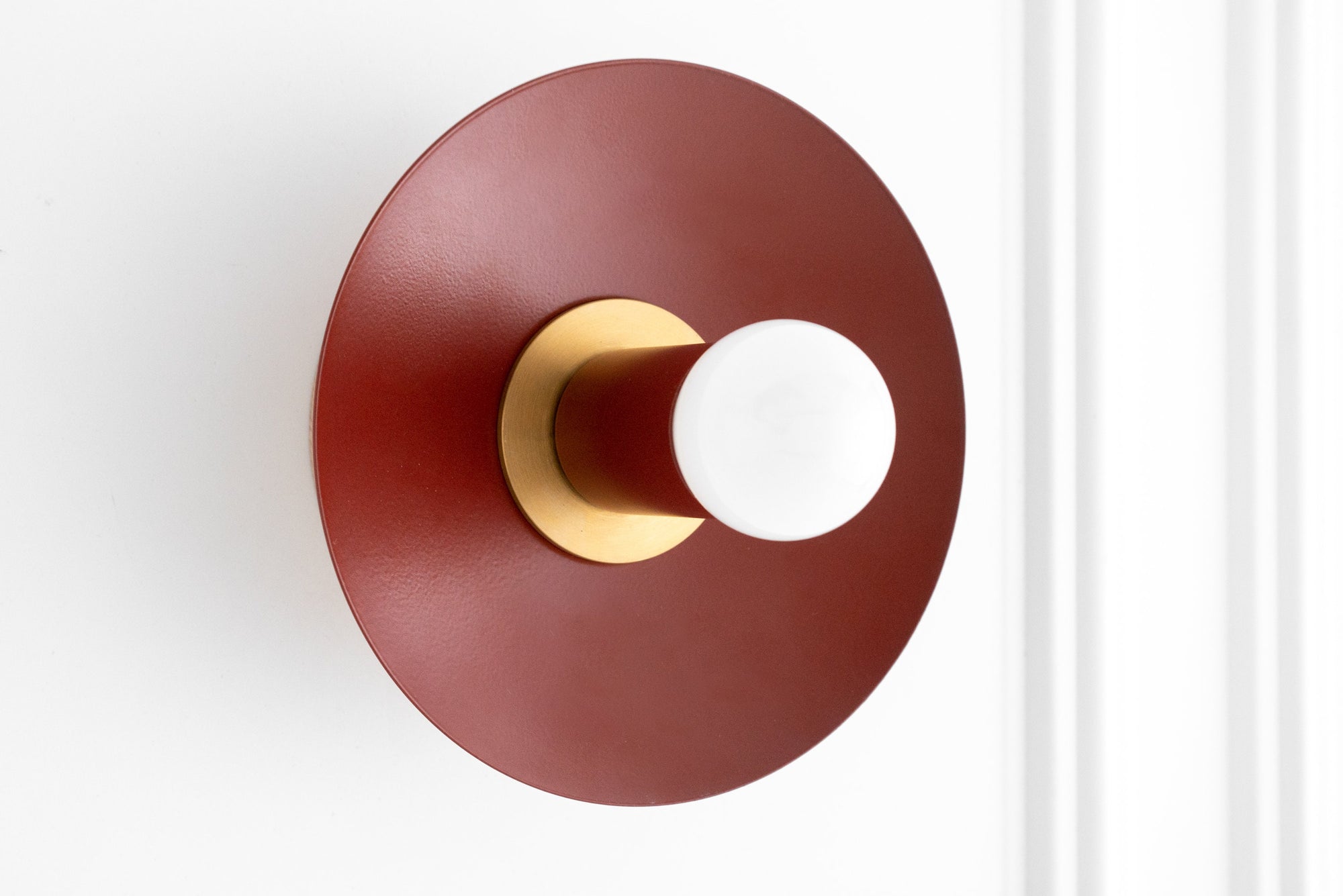 Wall sconce with raw brass fixture and round brick red backplate with exposed bulb. - SCONCE MODEL NO. 9660