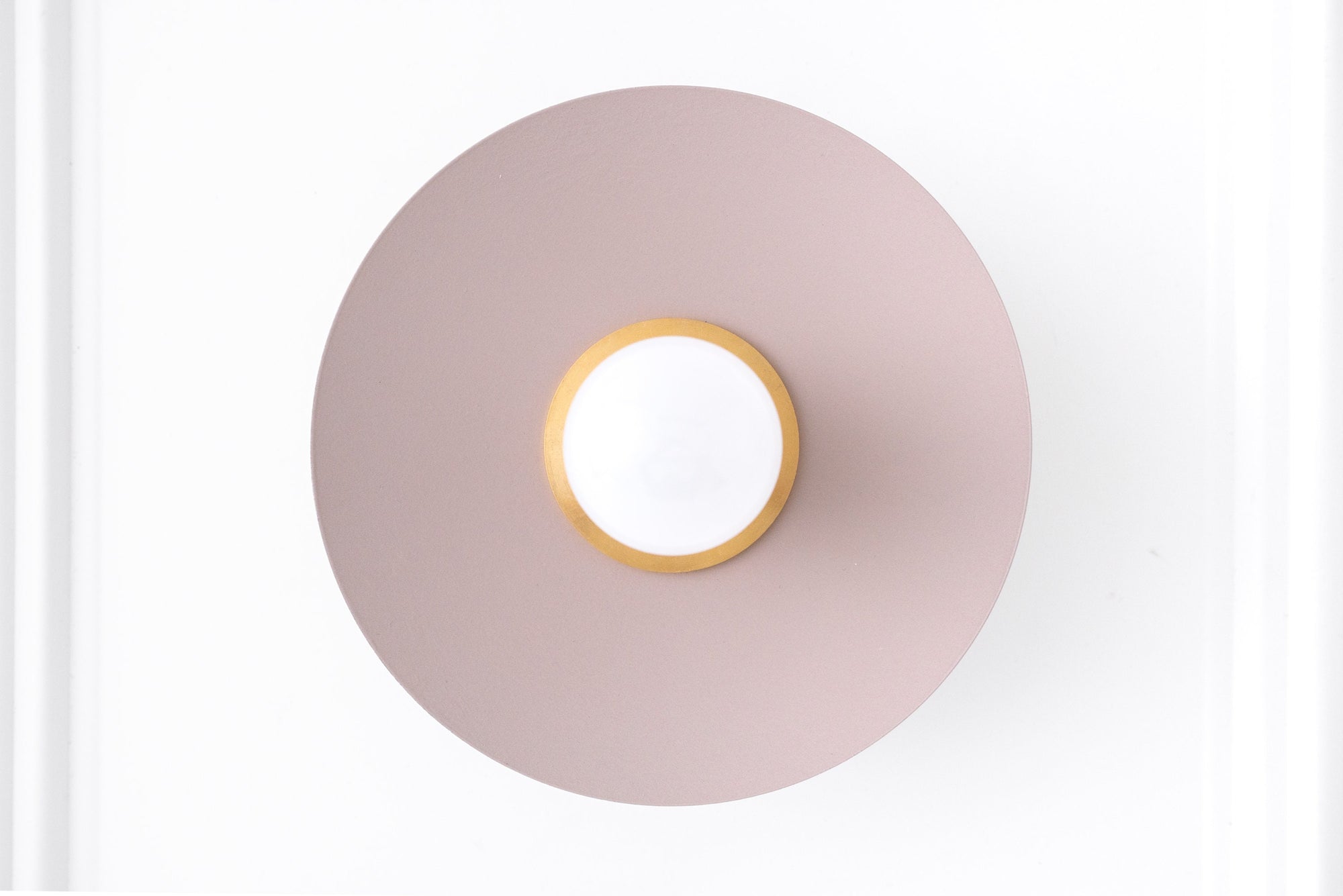 Scandinavian style wall sconce with raw brass center and mauve circular backplate. - SCONCE MODEL NO. 9660