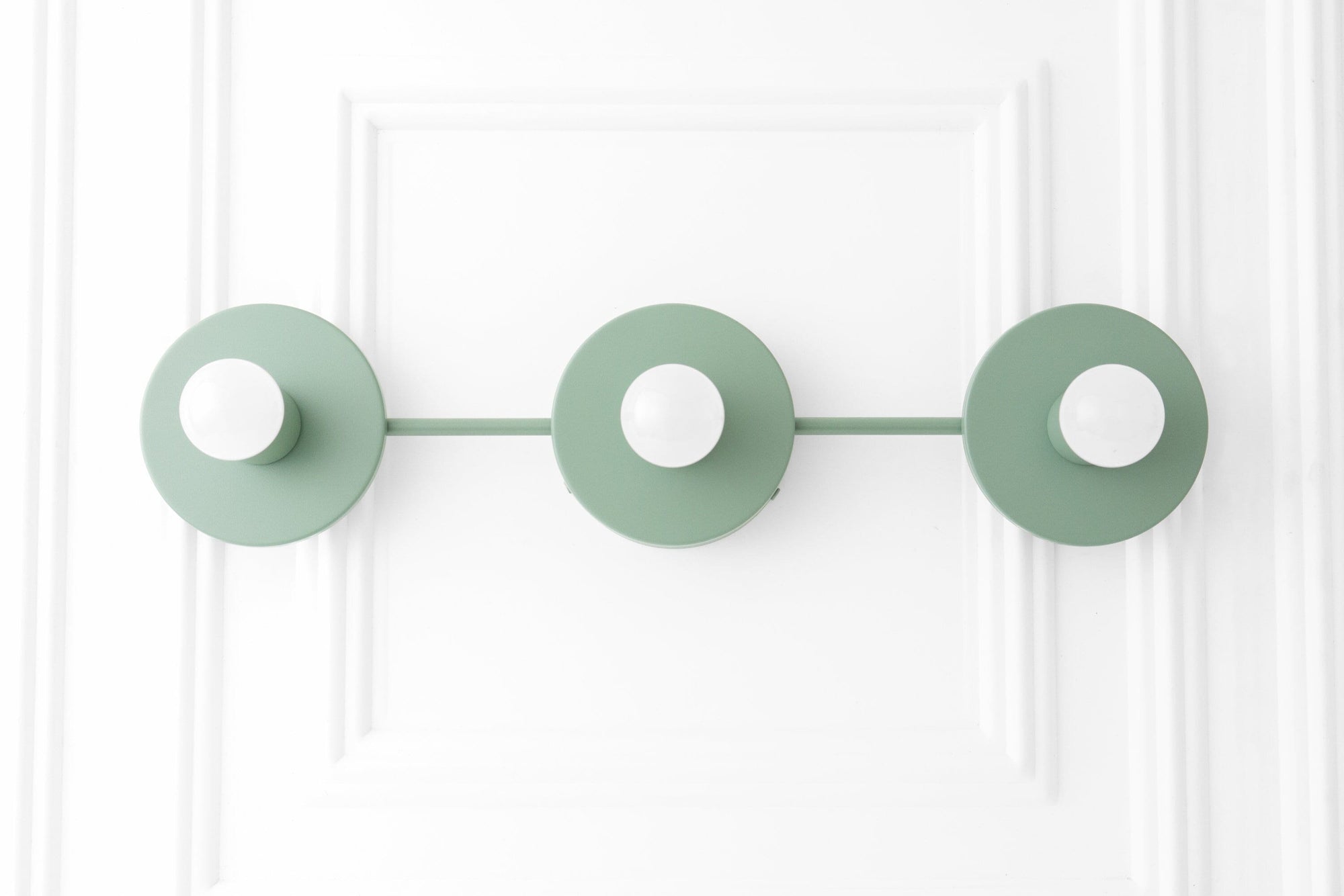 Scandinavian style vanity light with three matte green circular shades and exposed bulbs on a horizontal bar. - VANITY LIGHT MODEL NO. 5708