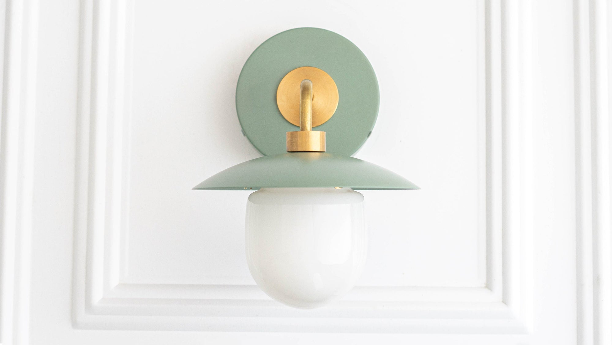 Mid-century modern sconce with raw brass fixture and muted green circular backplate and shade, frosted globe bulb. - SCONCE MODEL NO. 7039