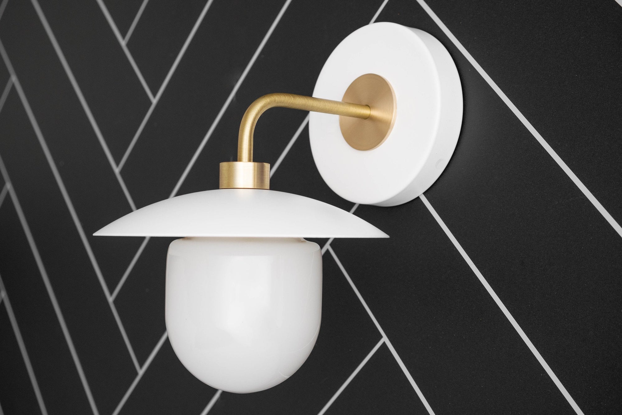 Mid-century modern wall sconce with raw brass arm and white globe shade mounted on a white circular base. - SCONCE MODEL NO. 7039