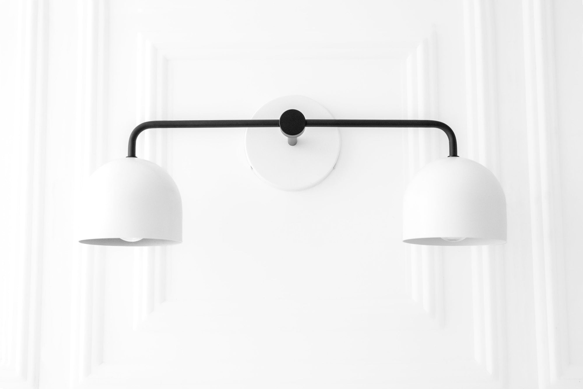 Matte black double-arm vanity light with two smooth white dome shades mounted on a white wall background. - VANITY LIGHT MODEL NO. 2082