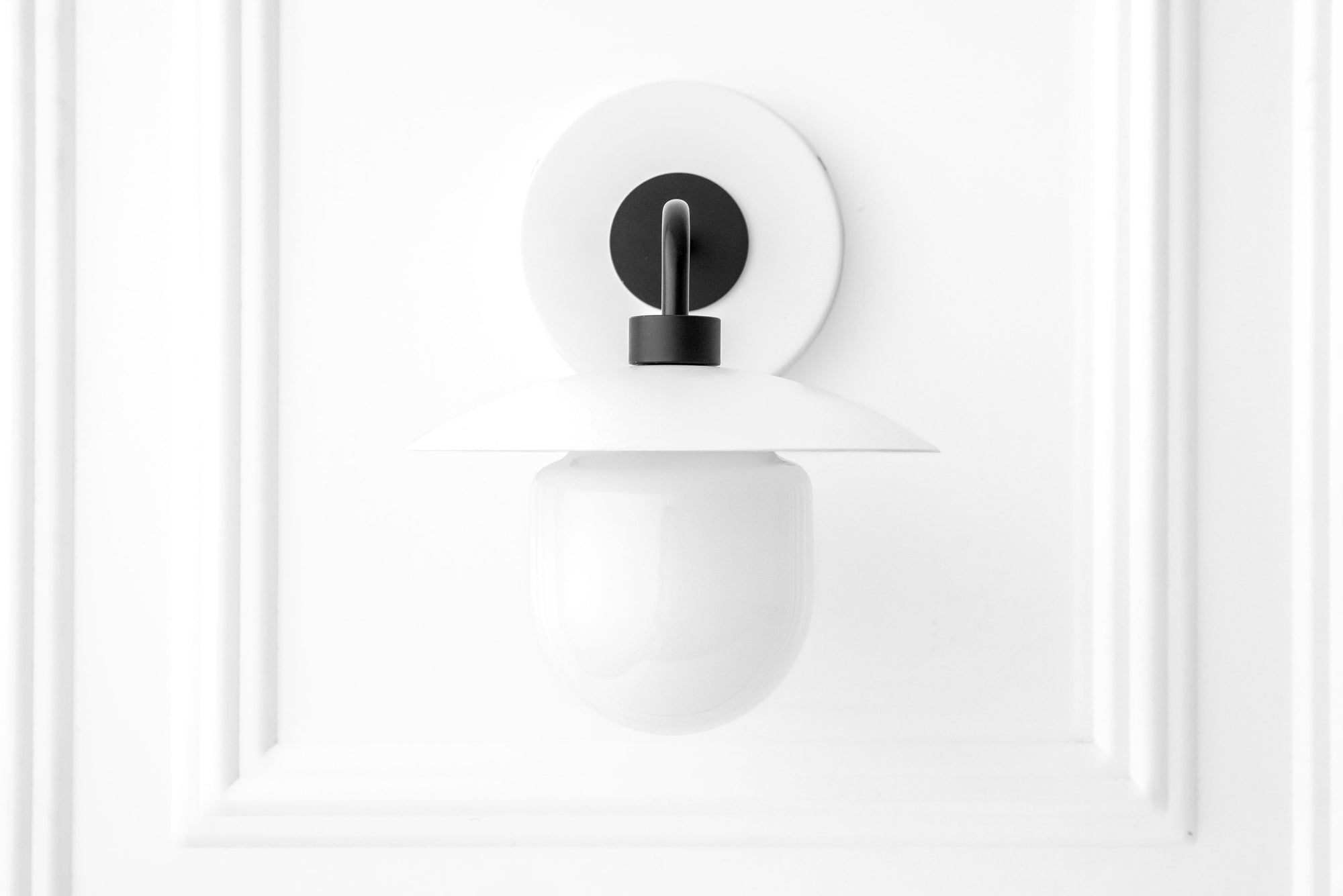 Scandinavian-style wall sconce with a black metal mount and opaque white glass globe shade. - SCONCE MODEL NO. 7039