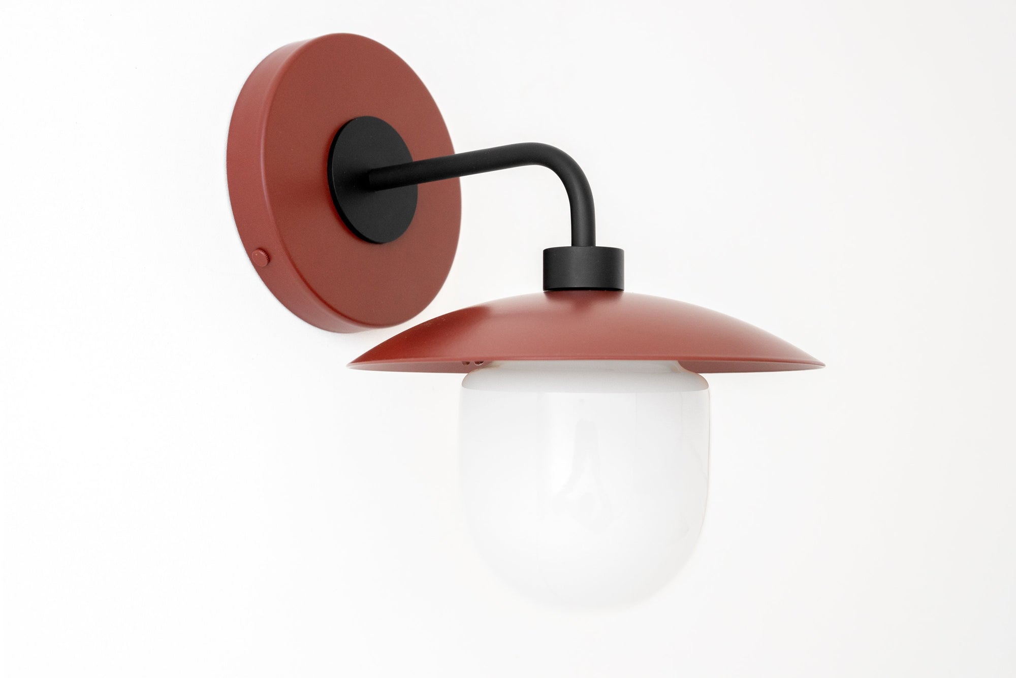 Black metal arm sconce with brick red circular backplate and shade, white globe diffuser. - SCONCE MODEL NO. 7039