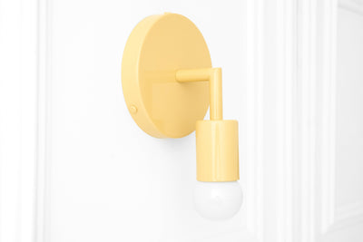 Matte yellow bare bulb wall sconce with cylindrical fixture on round backplate. - SCONCE MODEL NO. 5480