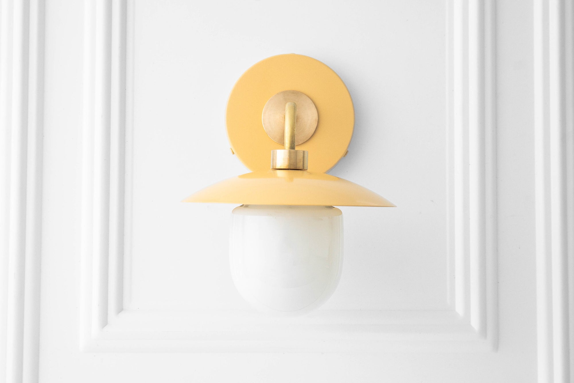Raw brass mid-century modern wall sconce with yellow circular metal shade and white globe glass diffuser. - SCONCE MODEL NO. 7039