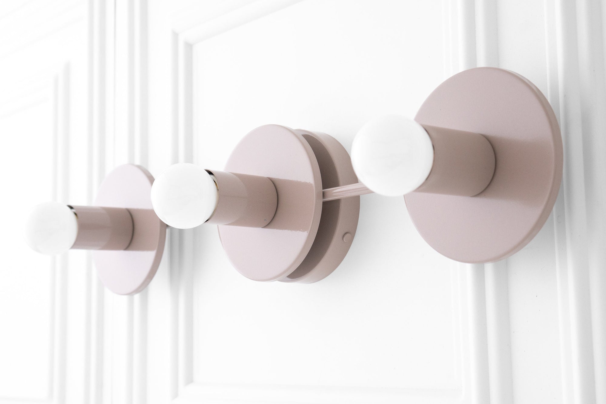 Three-bulb vanity light in mauve with cylindrical sockets and round backplates on white wall. - VANITY LIGHT MODEL NO. 5708