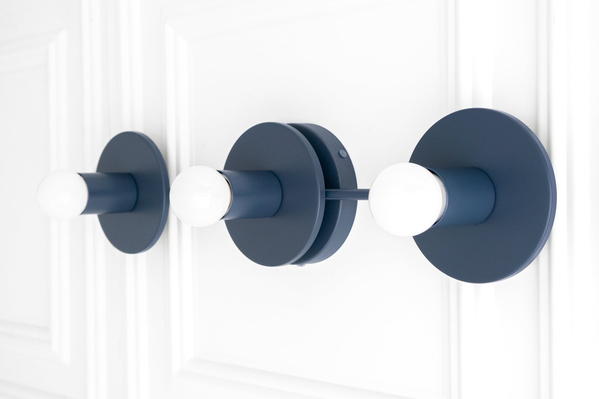 Matte coal blue three-bulb vanity light with exposed round white bulbs and circular backplates. - VANITY LIGHT MODEL NO. 5708