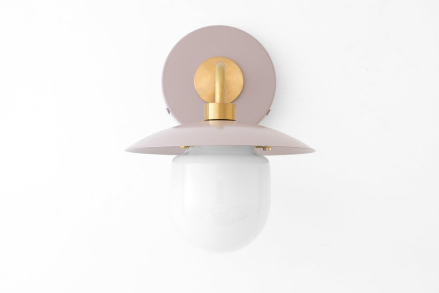 Mid-century modern wall sconce with raw brass fixture and mauve metal backplate and shade, white globe shade. - SCONCE MODEL NO. 7039