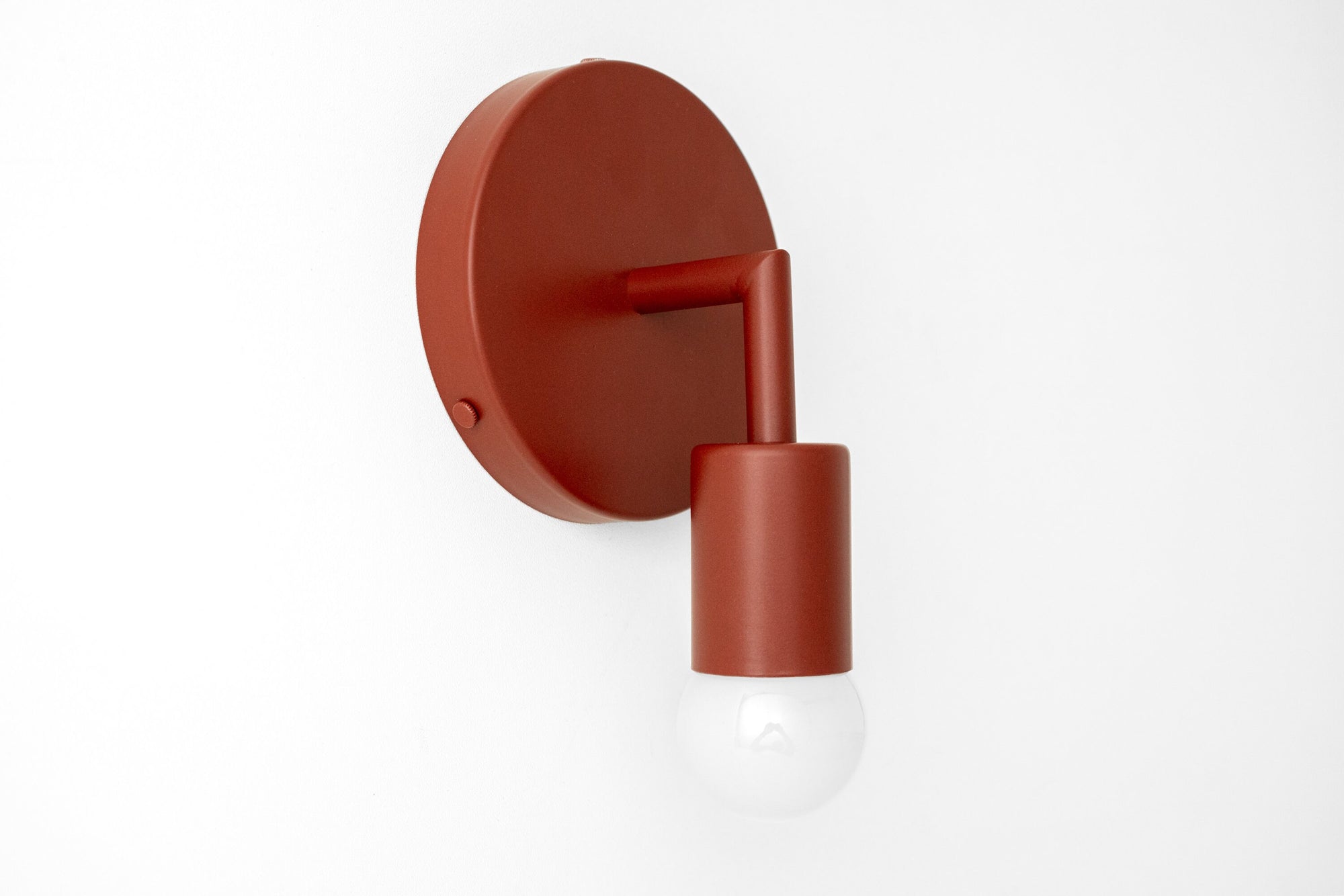 Brick red Scandinavian-style wall sconce with bare bulb and cylindrical arm. - SCONCE MODEL NO. 5480