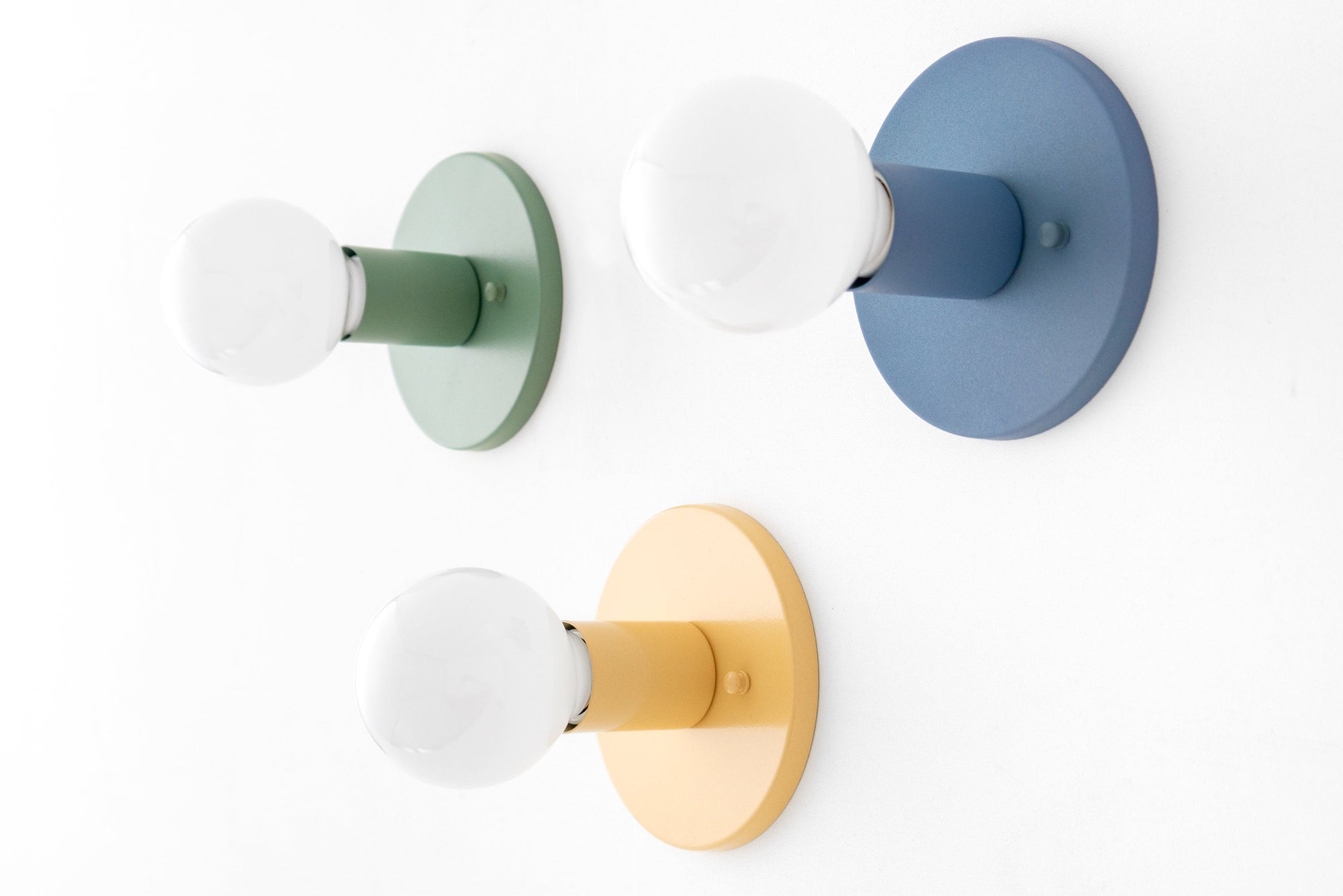 Set of three mid-century modern wall sconces with round backplates in green, blue, and yellow, each featuring a bare bulb. - SCONCE MODEL NO. 4460