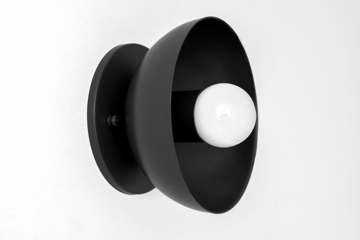 Matte black Scandinavian-style flush mount sconce with exposed white bulb and curved shade. - SCONCE MODEL NO. 4812