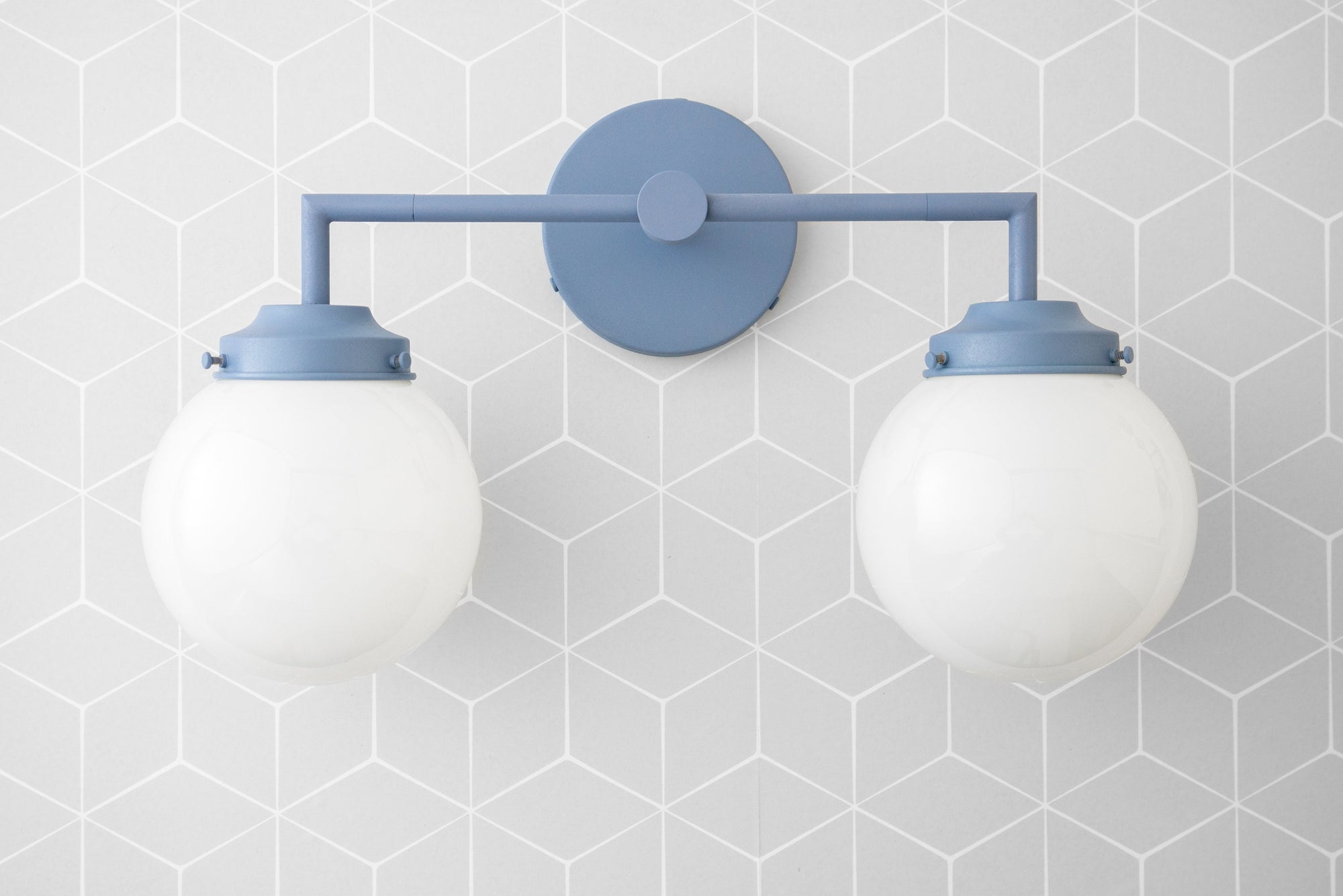 Two-bulb vanity light with coal blue metal fixture and round white globe shades against a gray hexagonal tile wall. - VANITY LIGHT MODEL NO. 9500