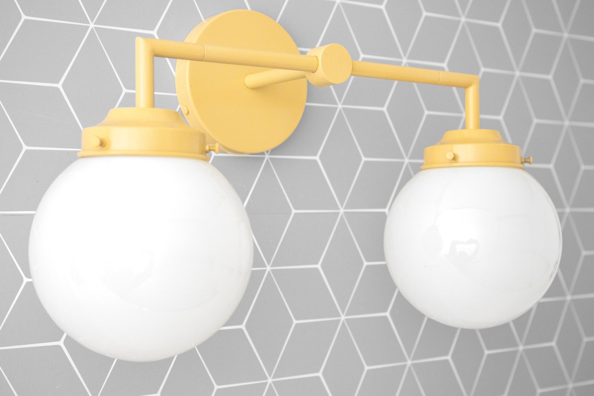 Two-bulb yellow metal vanity light with large white glass globe shades on gray geometric tile background. - VANITY LIGHT MODEL NO. 9500