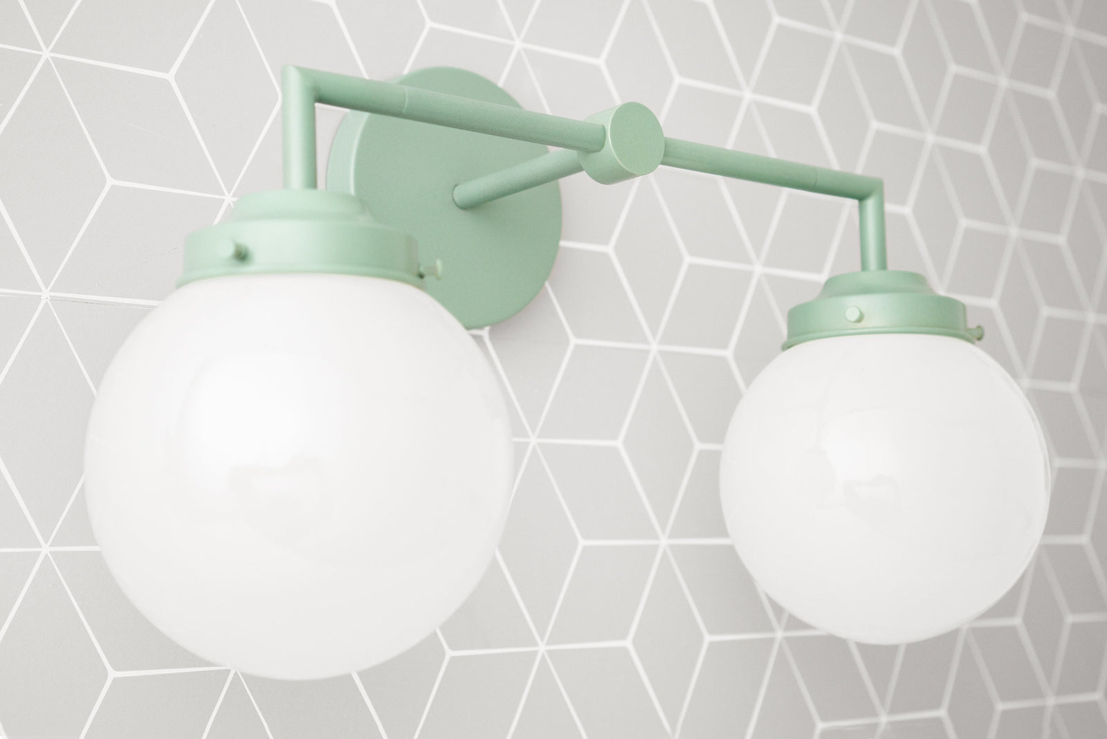Vanity light with two white glass globes and matte green metal frame mounted on geometric gray wall. - VANITY LIGHT MODEL NO. 9500