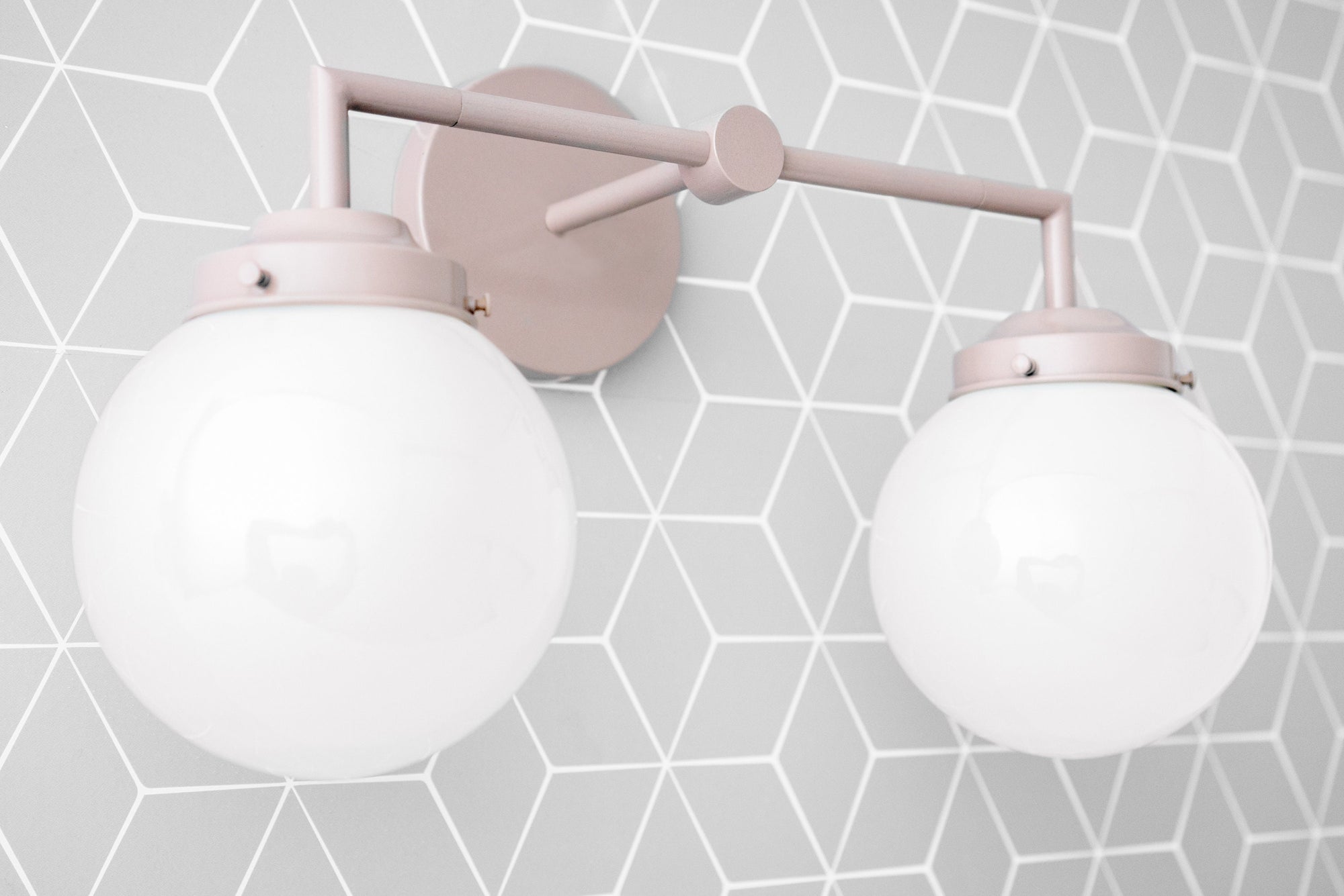 Two-bulb vanity light with mauve matte metal fixtures and round white glass globes on geometric wall background. - VANITY LIGHT MODEL NO. 9500