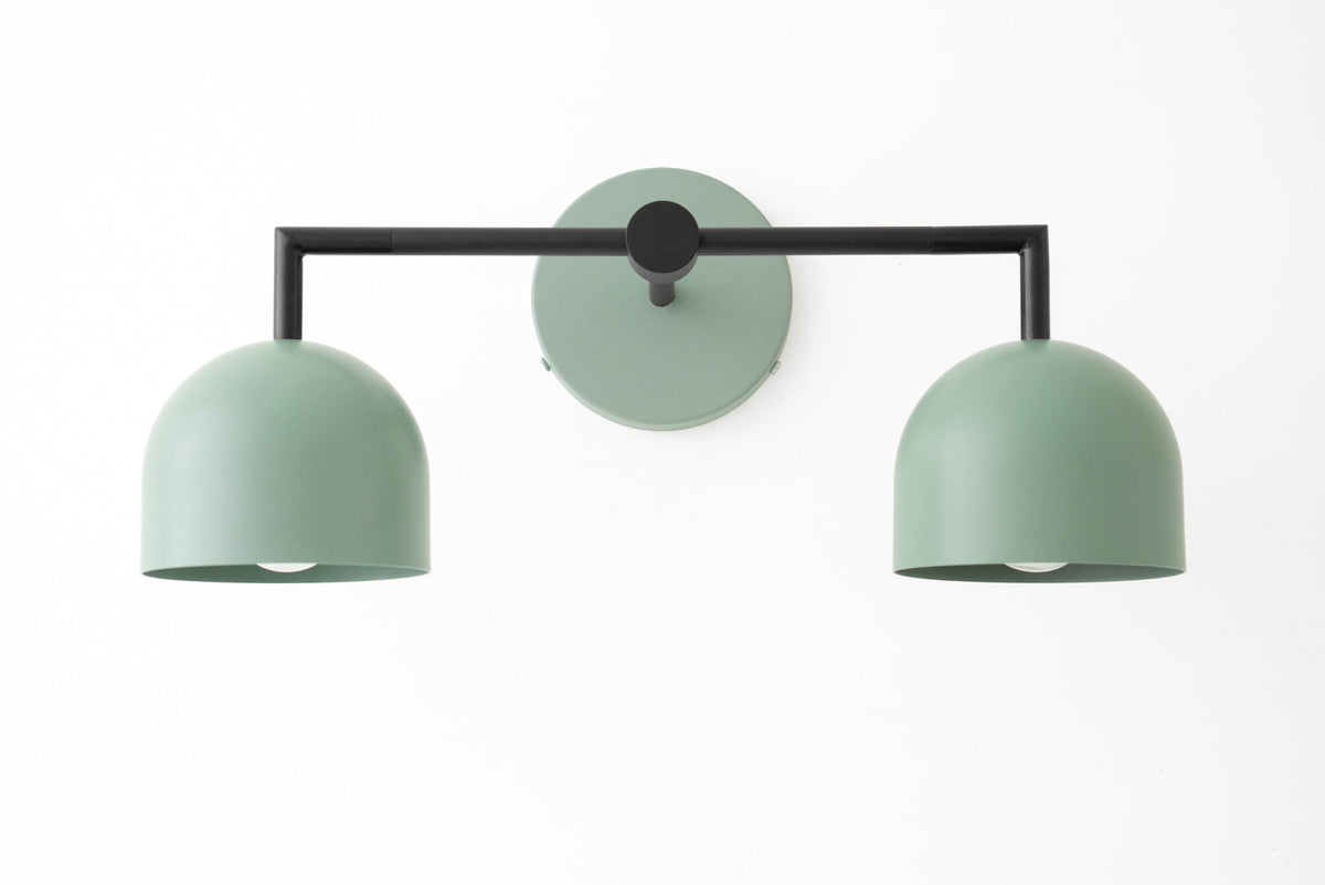 Matte green dual shade vanity light with black frame and round wall mount in modern Art Deco style. - VANITY LIGHT MODEL NO. 8432