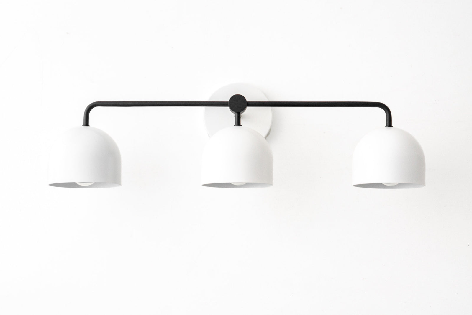Mid-century modern 3-bulb vanity light with matte black bar and white dome shades. - VANITY LIGHT MODEL NO. 7456