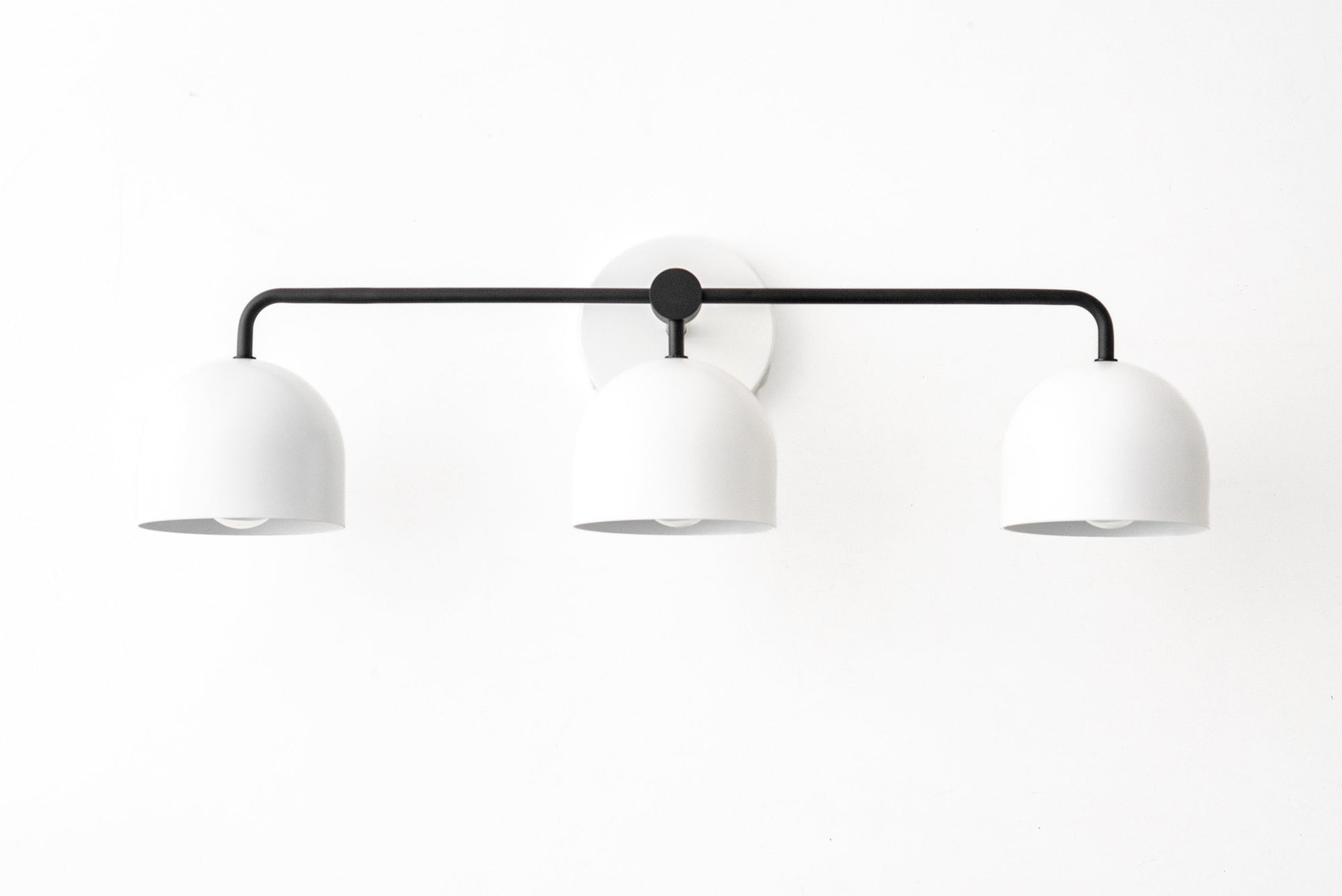 Mid-century modern 3-bulb vanity light with matte black bar and white dome shades. - VANITY LIGHT MODEL NO. 7456