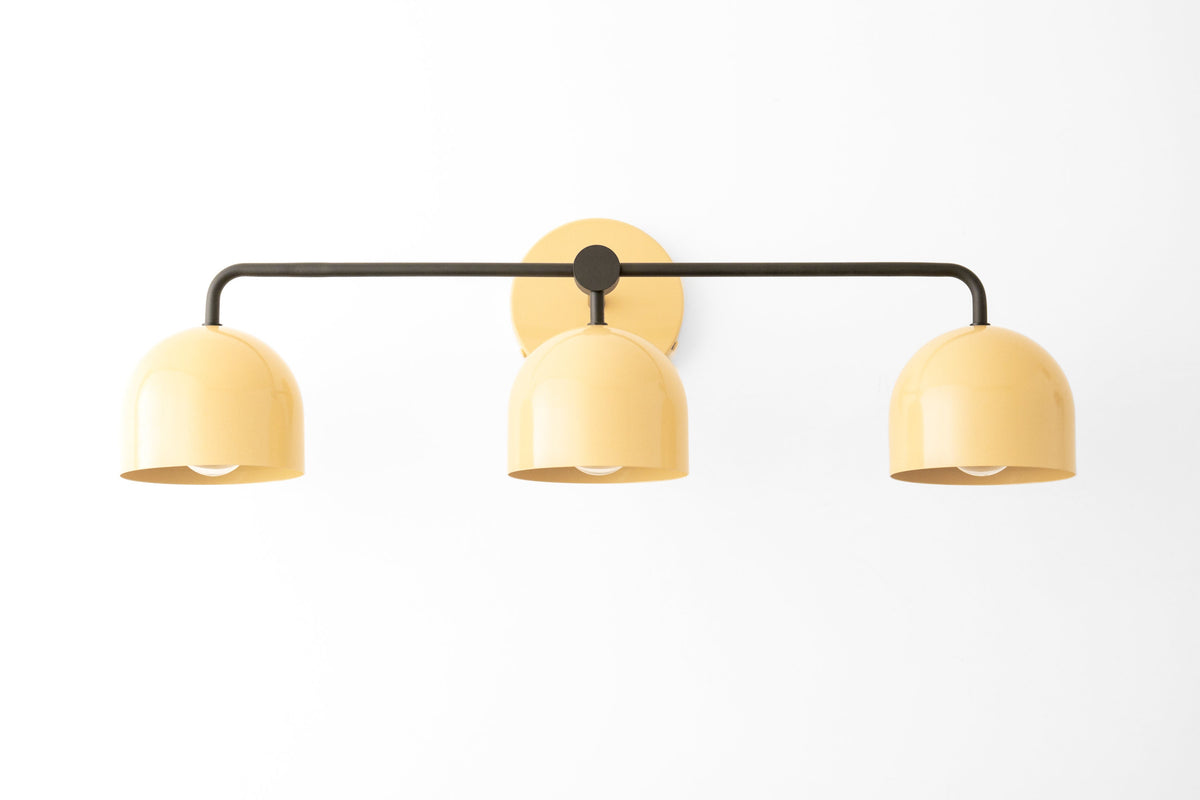 Mid-century modern vanity light with three pale yellow metal shades and black horizontal bar. - VANITY LIGHT MODEL NO. 7456