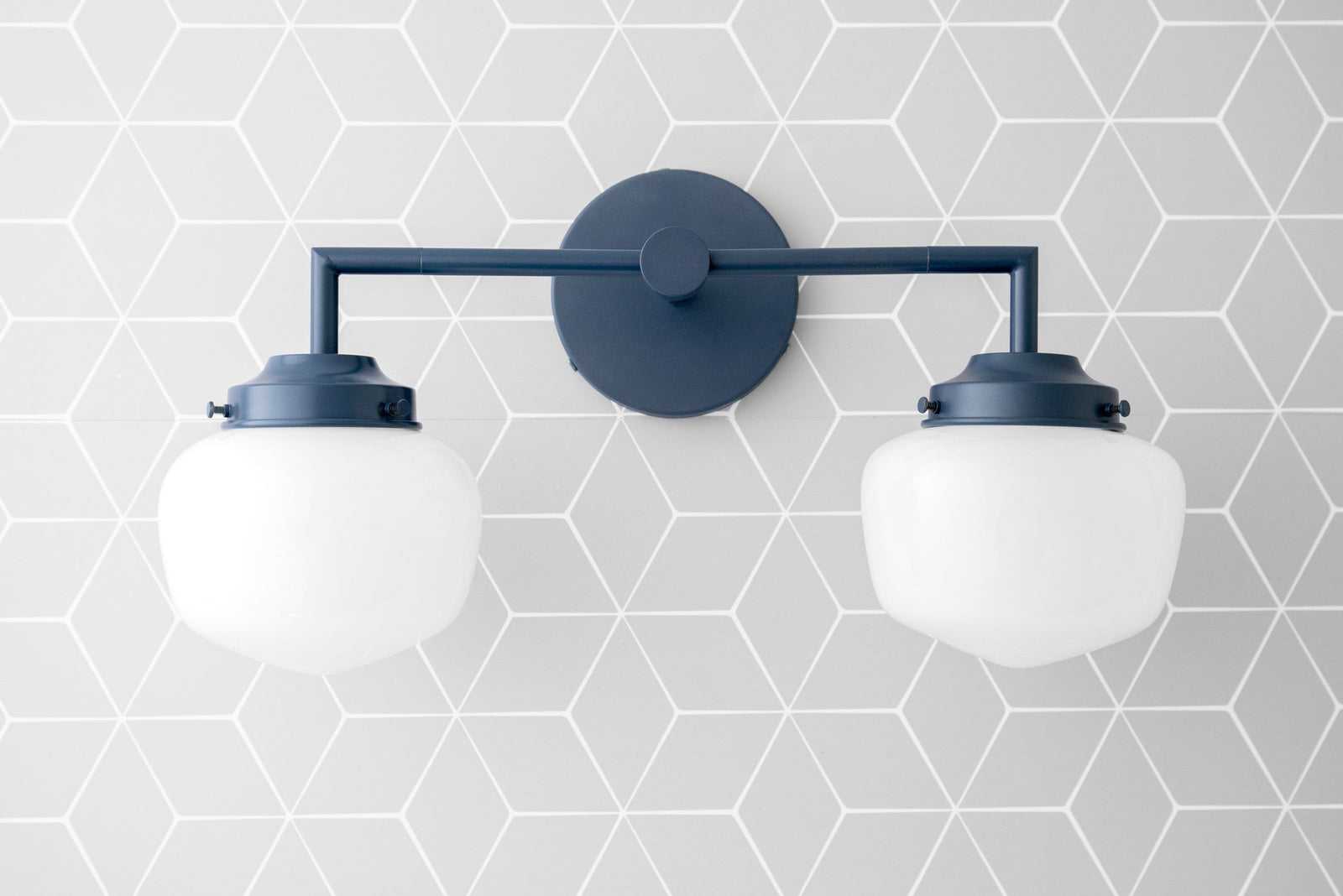 Coal blue two-bulb vanity light with matte finish and white globe shades mounted on geometric patterned wall. - VANITY LIGHT MODEL NO. 0276