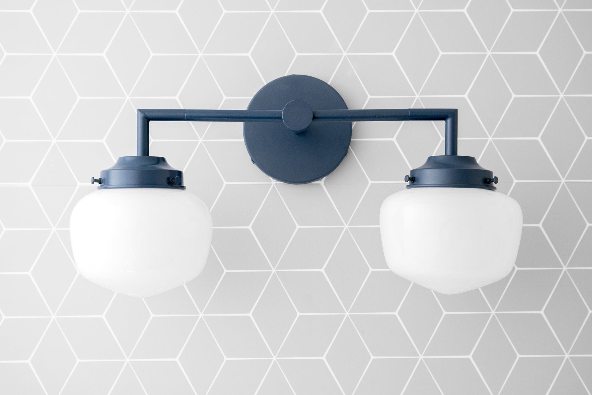 Black metal two-bulb vanity light with white globe shades and geometric patterned gray wall background. - VANITY LIGHT MODEL NO. 0276
