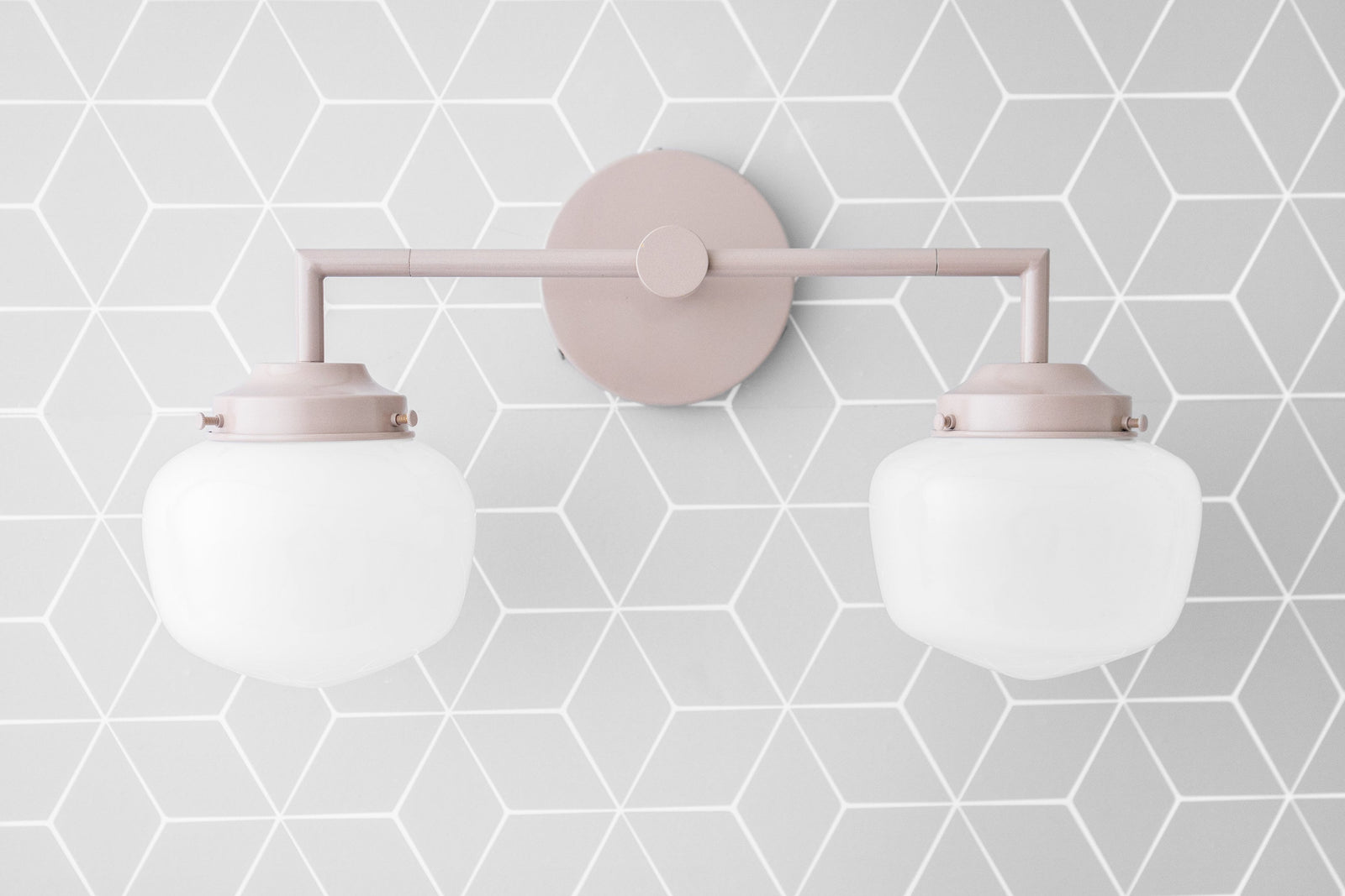 Art Deco style 2-bulb vanity light in soft mauve with round white glass globes and geometric gray wallpaper background. - VANITY LIGHT MODEL NO. 0276