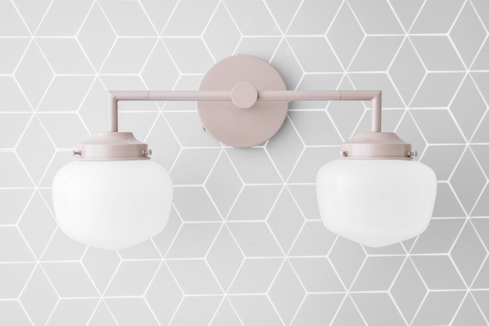Art Deco style 2-bulb vanity light in soft mauve with round white glass globes and geometric gray wallpaper background. - VANITY LIGHT MODEL NO. 0276