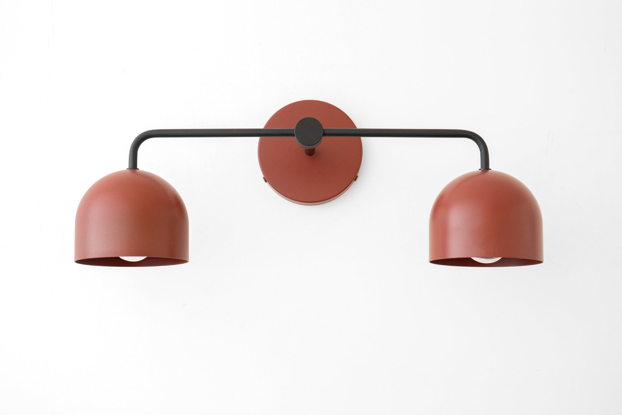 Black metal vanity light with two deep brick red dome shades and a central round wall mount. - VANITY LIGHT MODEL NO. 2082