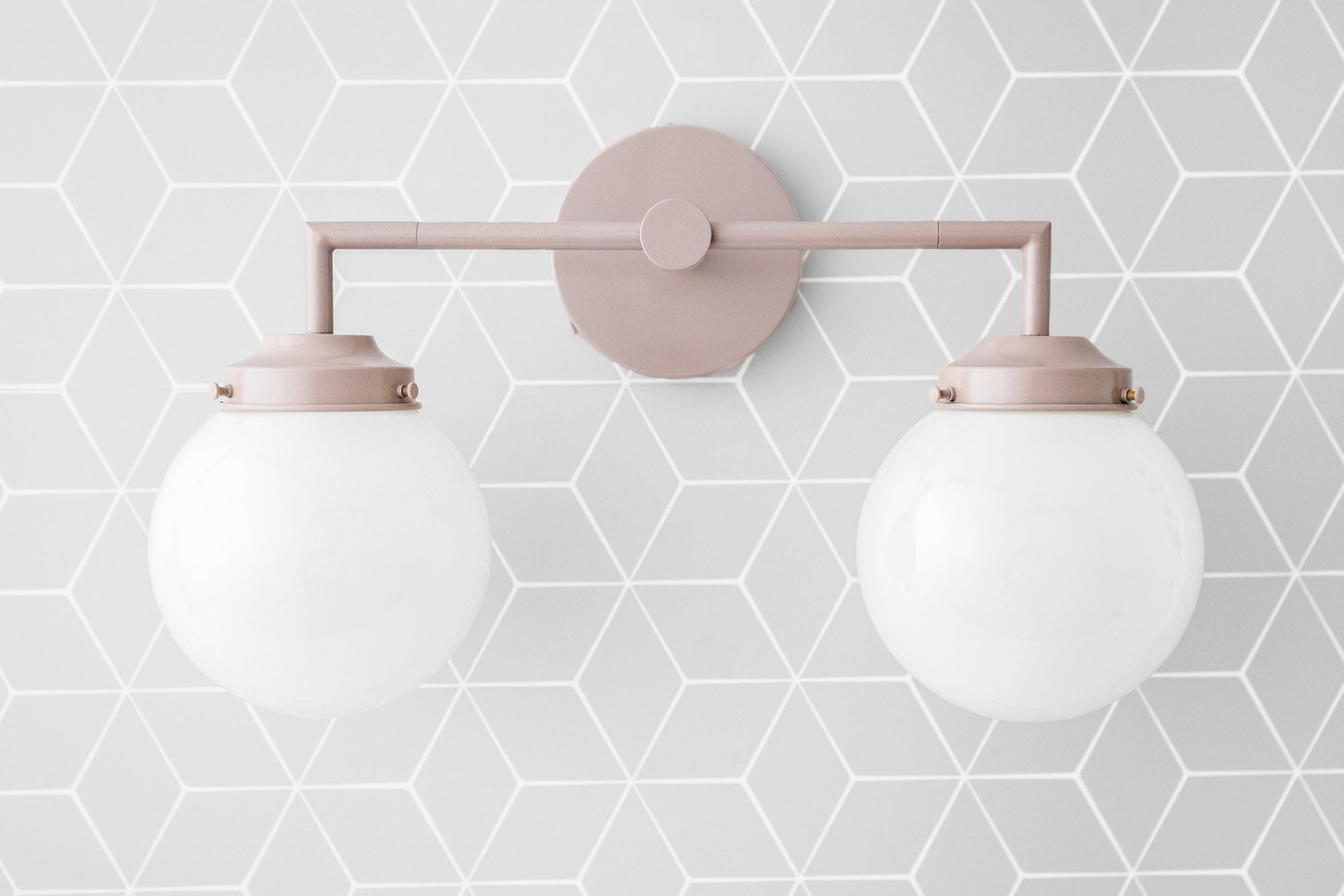Mauve vanity light with two white globe bulbs mounted on geometric patterned wall. - VANITY LIGHT MODEL NO. 9500
