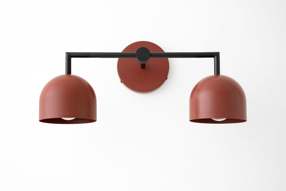 Black metal double-arm wall vanity light with deep brick red dome shades, Art Deco style. - VANITY LIGHT MODEL NO. 8432
