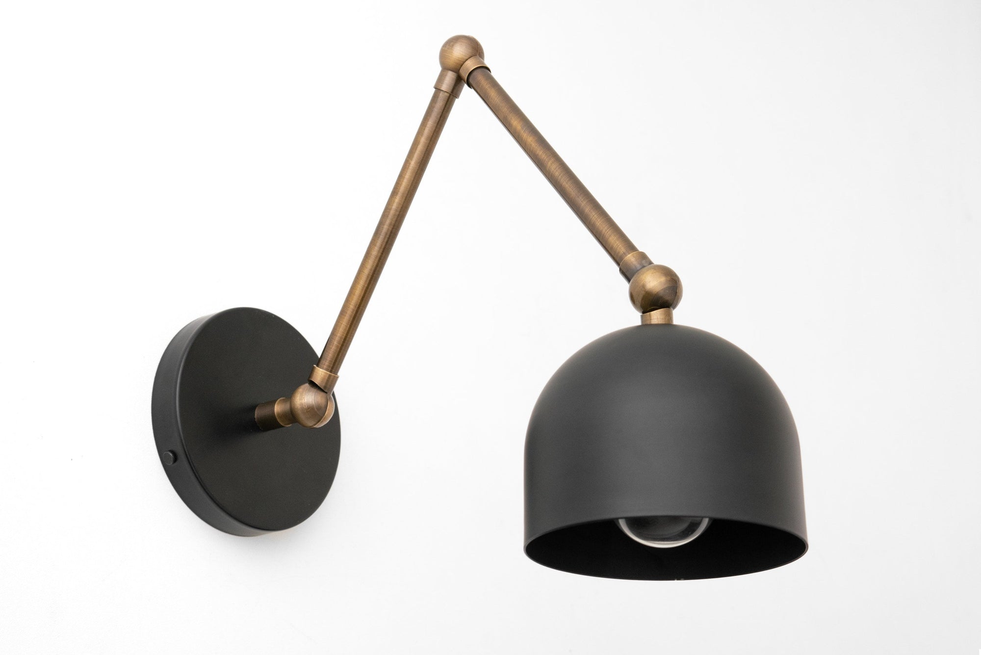 Adjustable wall sconce with matte black dome shade and antique brass arm. - SCONCE MODEL NO. 5998