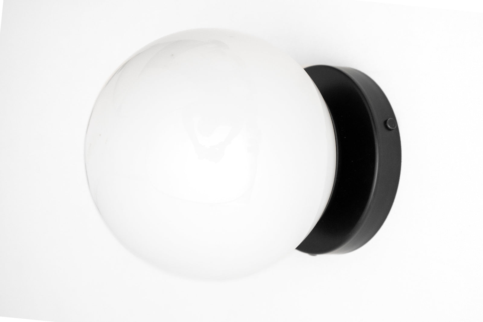Mid-century modern wall sconce with a white glass globe and black circular flush mount. - SCONCE MODEL NO. 3825