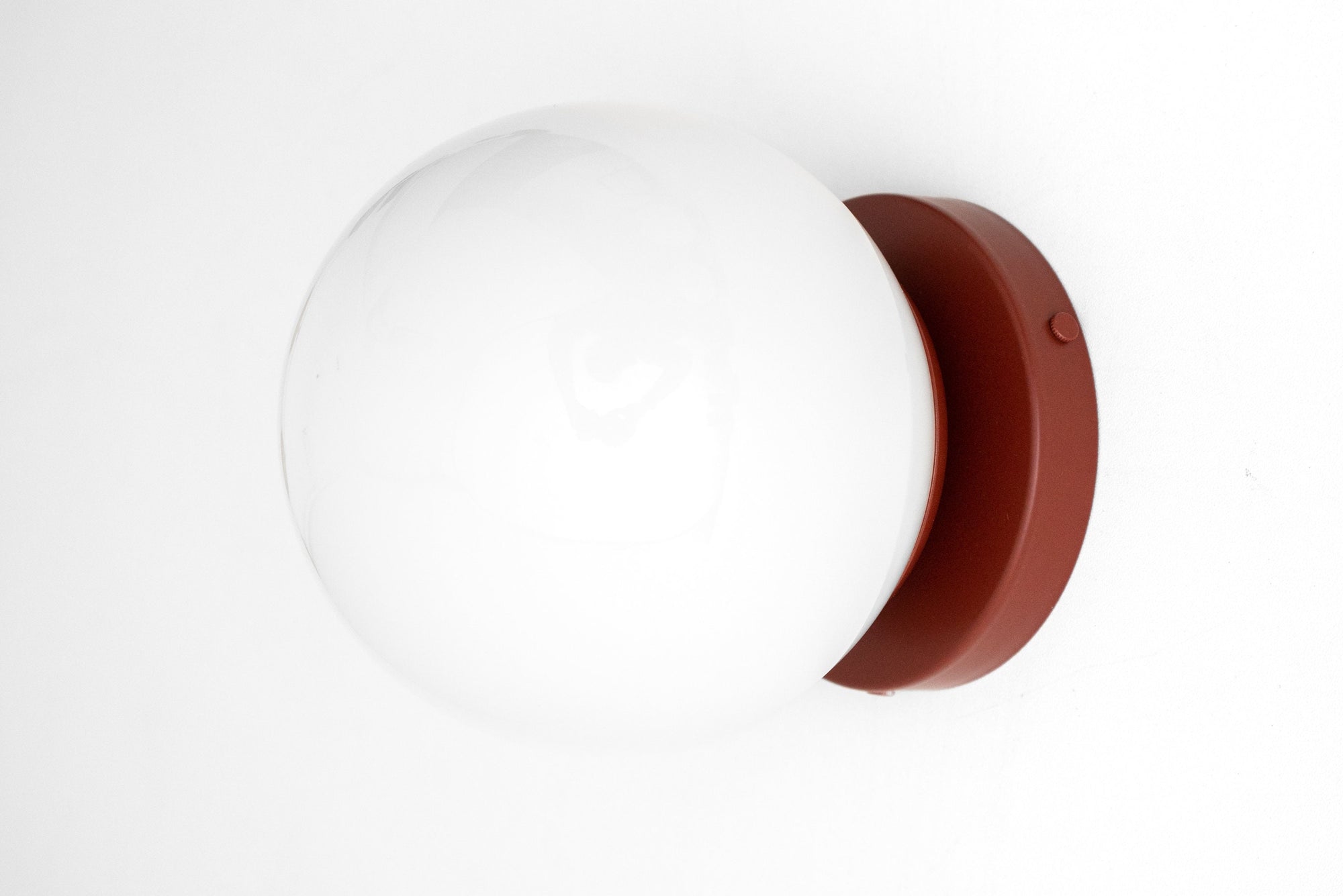 Mid-century modern sconce with a white frosted glass globe and brick red flush mount base. - SCONCE MODEL NO. 3825