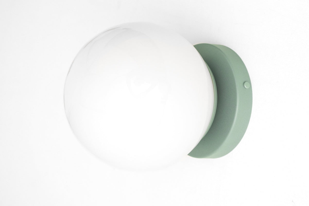 Mid-century modern wall sconce with a white globe and matte pastel green flush mount. - SCONCE MODEL NO. 3825