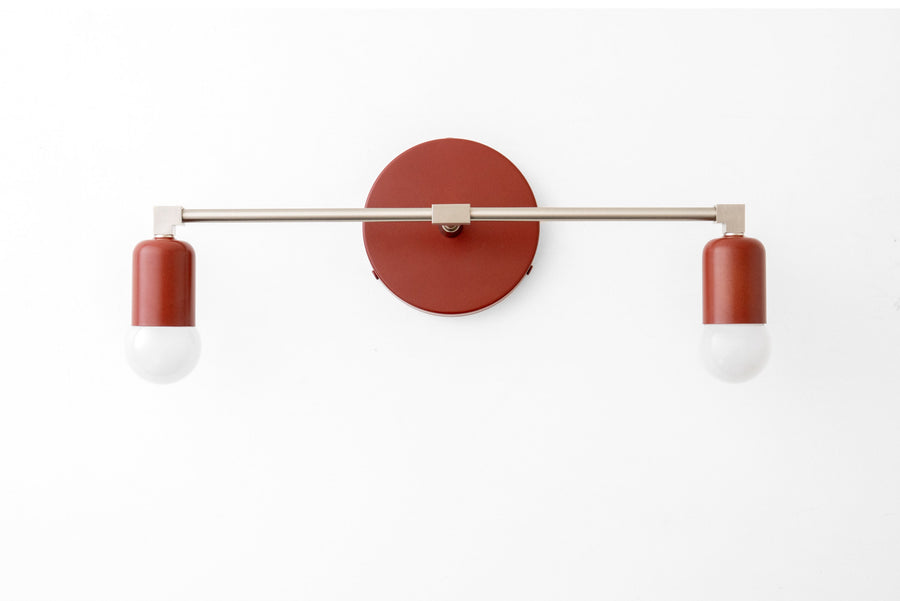 Mid-century modern 2-bulb vanity light with brick red bare bulb shades and brushed nickel horizontal bar and round wall mount. - VANITY LIGHT MODEL NO. 0026